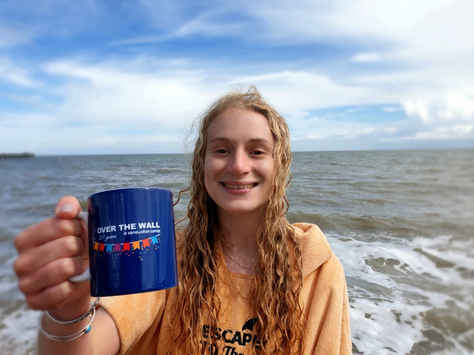 Volunteer Maddie with a mug of tea at the beach
