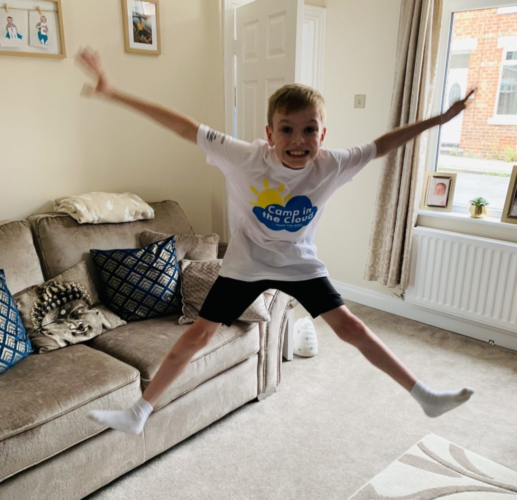 Boy jumping in the air in his lounge while taking part in Camp in the Cloud 2021