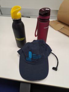 Blue hat, red water bottle, black and yellow water bottle