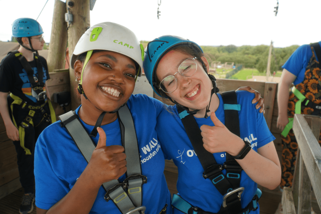 Two campers giving a thumbs up in hard hats ready to abseil.