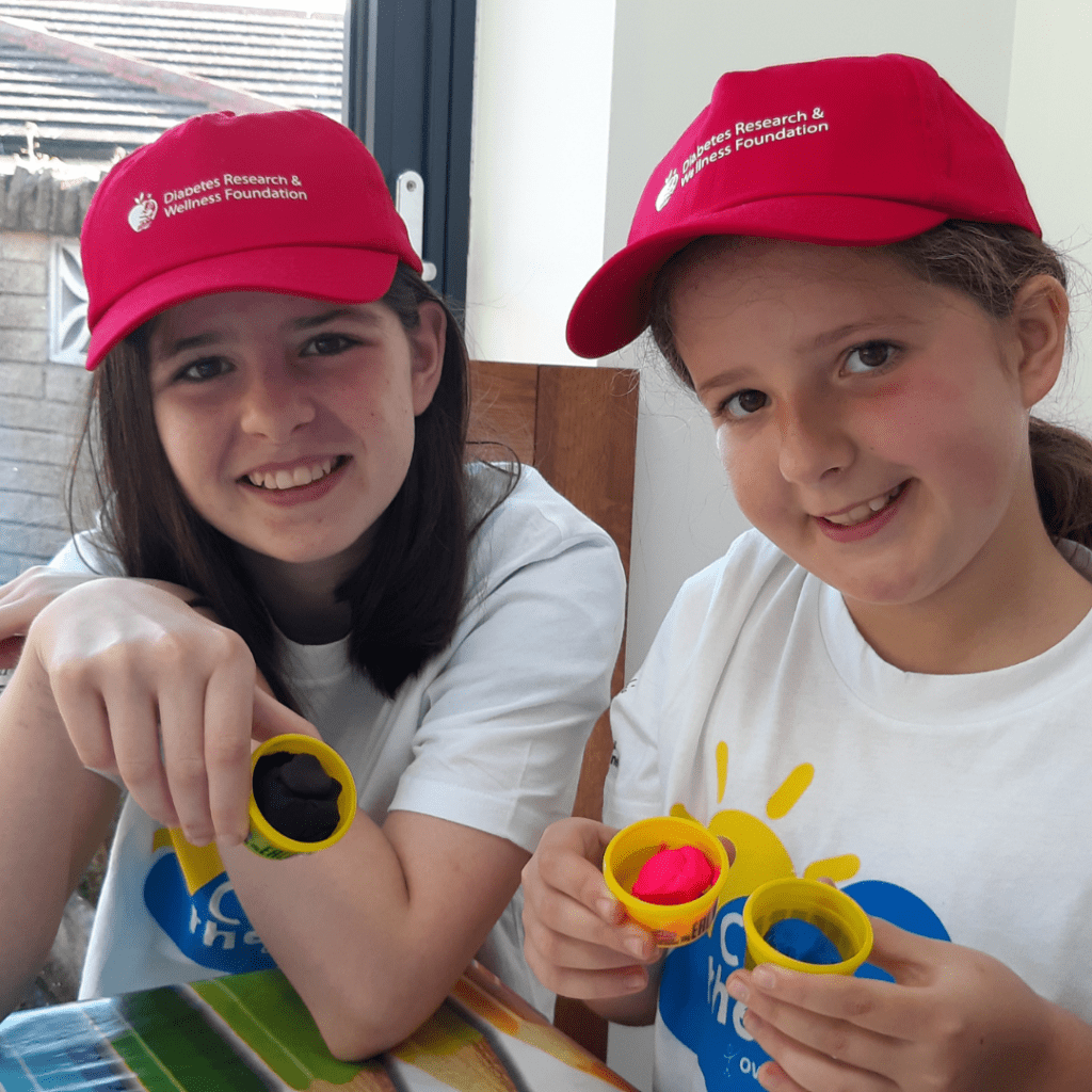 Two sisters wearing red DRWF baseball caps and Camp in the Cloud t-shirts.