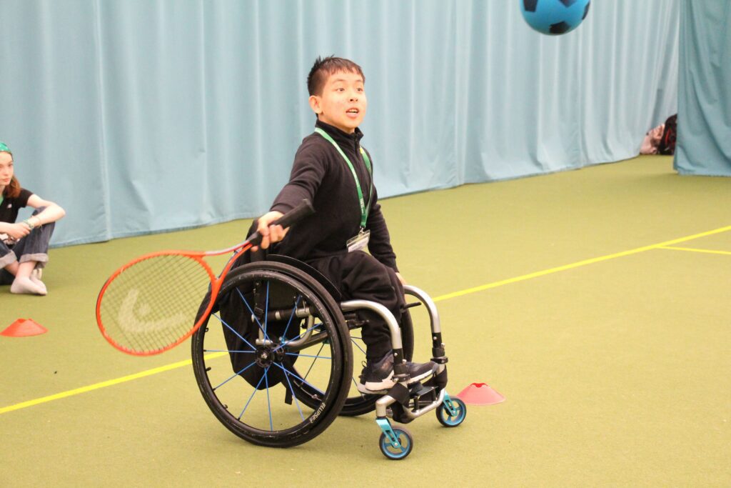 camper in a wheelchair playing tennis