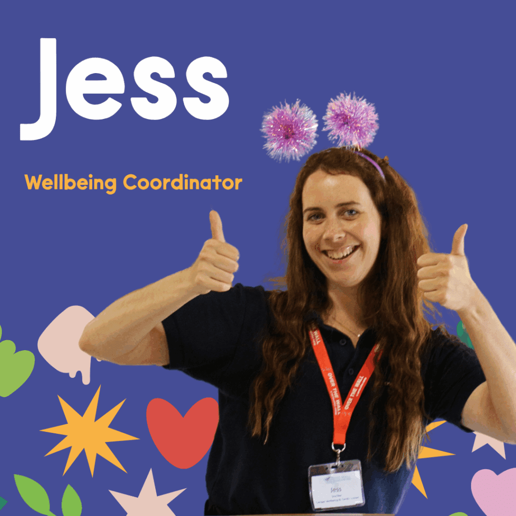 Jess, our wellbeing coordinator, with her thumbs up, smiling at the camera. She has pink sparkly head boppers on and the background is colourful OTWC icons