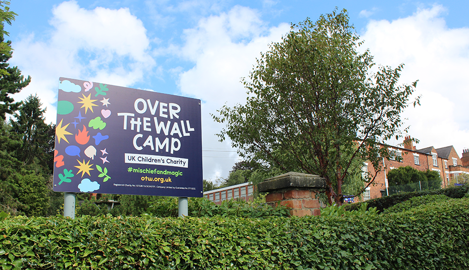Bright sign saying Over The Wall Camp in front of charity's grounds and gardens