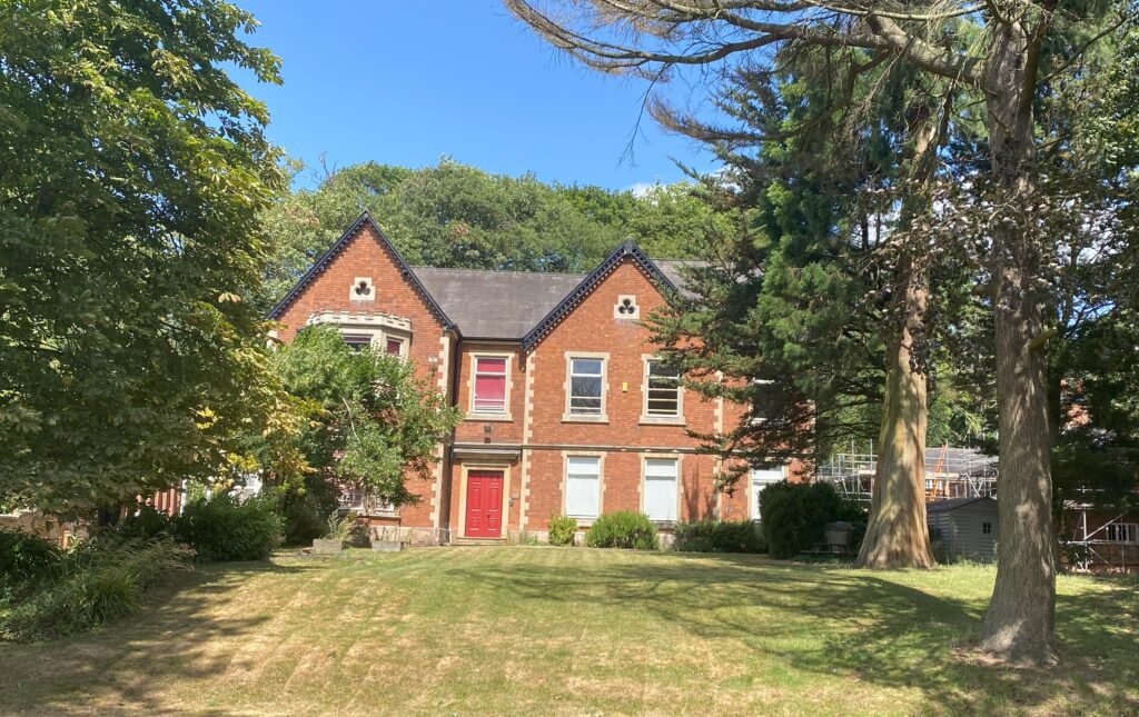 An 1800s school building with grounds and trees around it