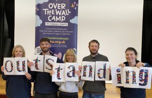 Over The Wall camp staff holding up posters which spell OUTSTANDING