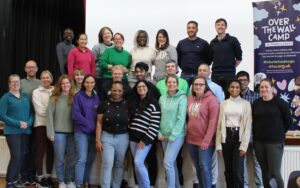 A large team of East Midlands paediatric registrars smiling by an Over The Wall Camp charity banner