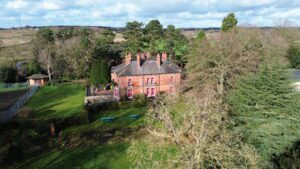Red brick school building nestled amongst trees and grounds