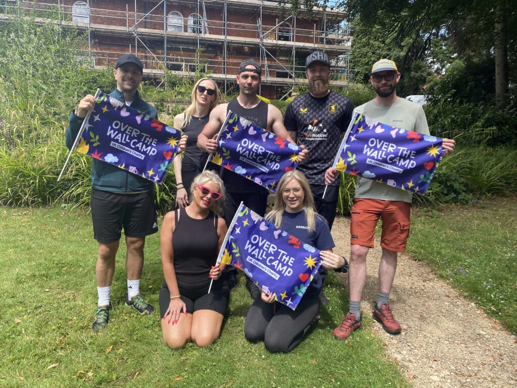 Group of Derbion staff smiling and holding OTWC flags