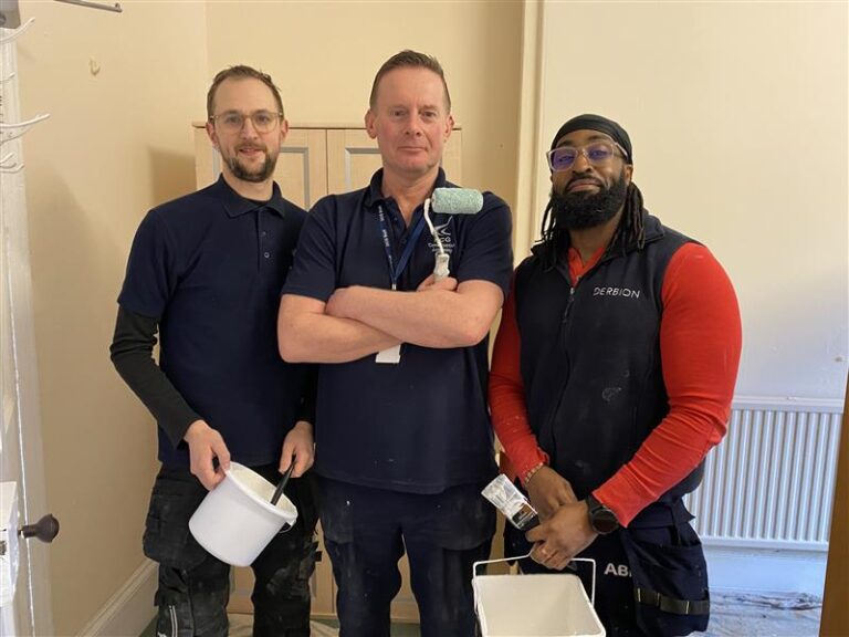 Three men holding painting materials