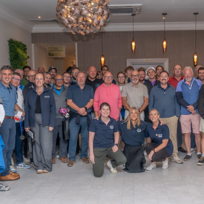 Large group of people smiling and posing for a photo to celebrate a charity Golf Day
