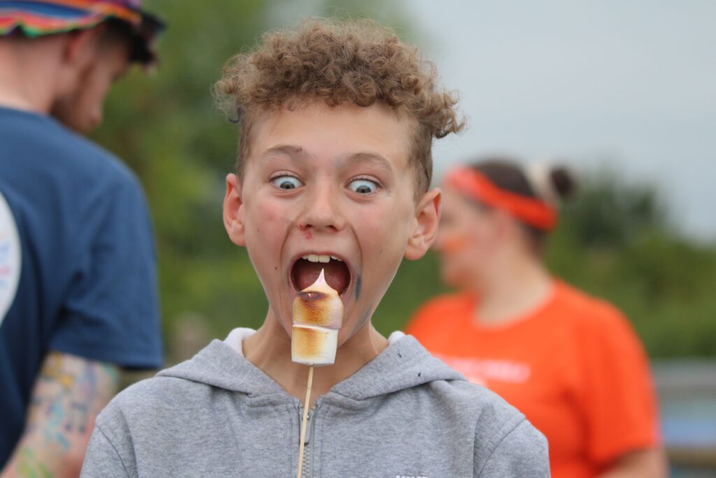 Young child in grey hoodies about to eat a toasted marshmallow