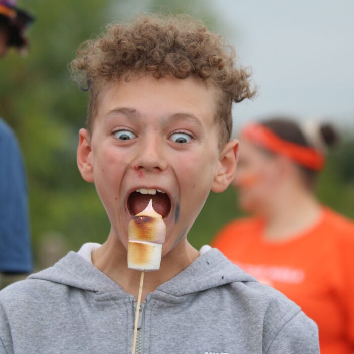 Young child in grey hoodies about to eat a toasted marshmallow