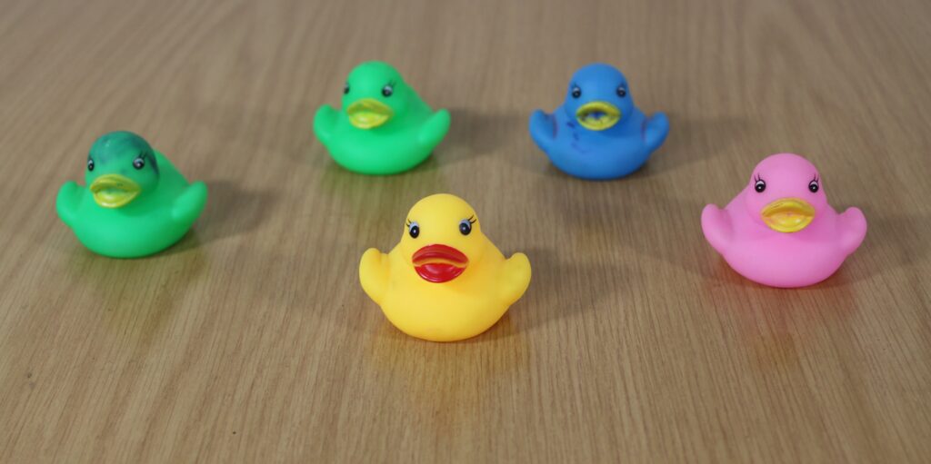 Five rubber ducks of different colours on a brown table